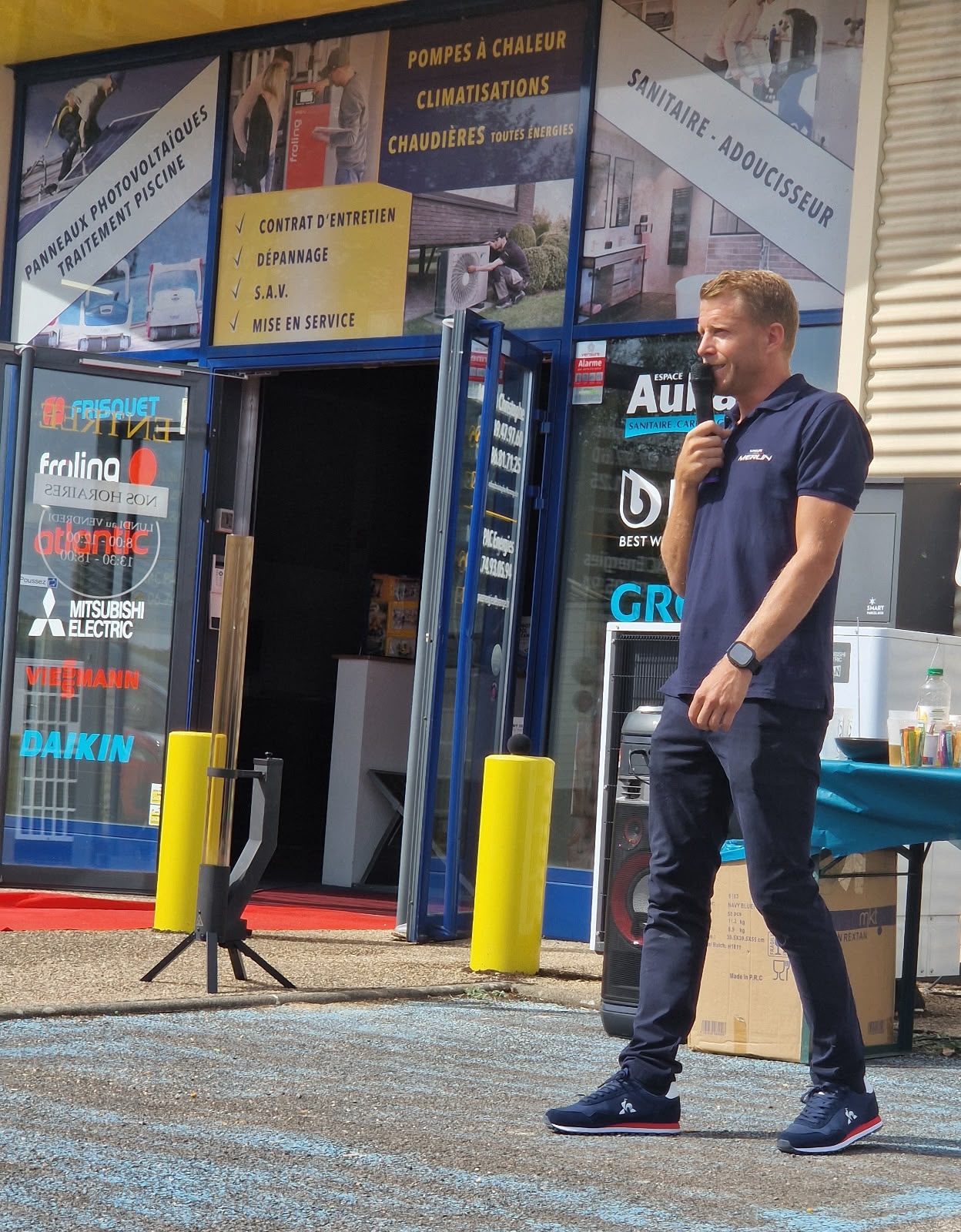 Christophe Merlin parle au micro devant la vitrine de l'agence Groupe Merlin de Clamecy
